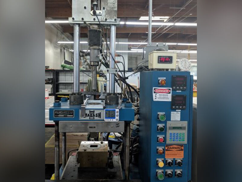 Image of compression molding equipment in a warehouse setting. 